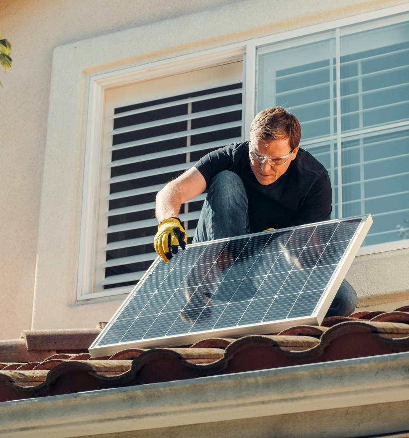 man op dak installeert zonnepanelen